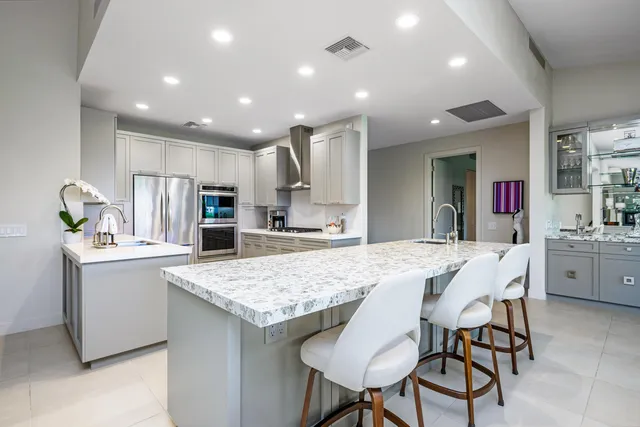 a kitchen with kitchen island granite countertop a sink a refrigerator and cabinets