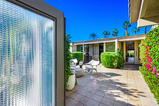 a view of a patio with table and chairs potted plants and a large tree
