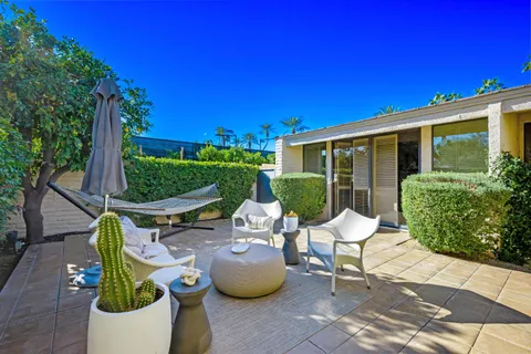 a view of a patio with a table and chairs under an umbrella with potted plants
