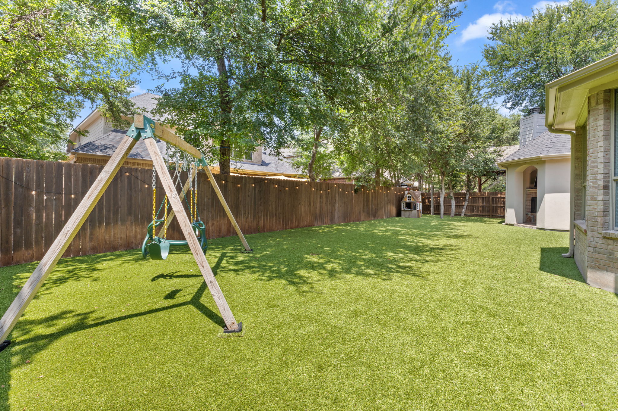 1124 Castle Path Round Rock, TX 78681 - Photo 39 of 40 A private, fenced backyard oasis with artificial turf, a swing set, and mature trees.