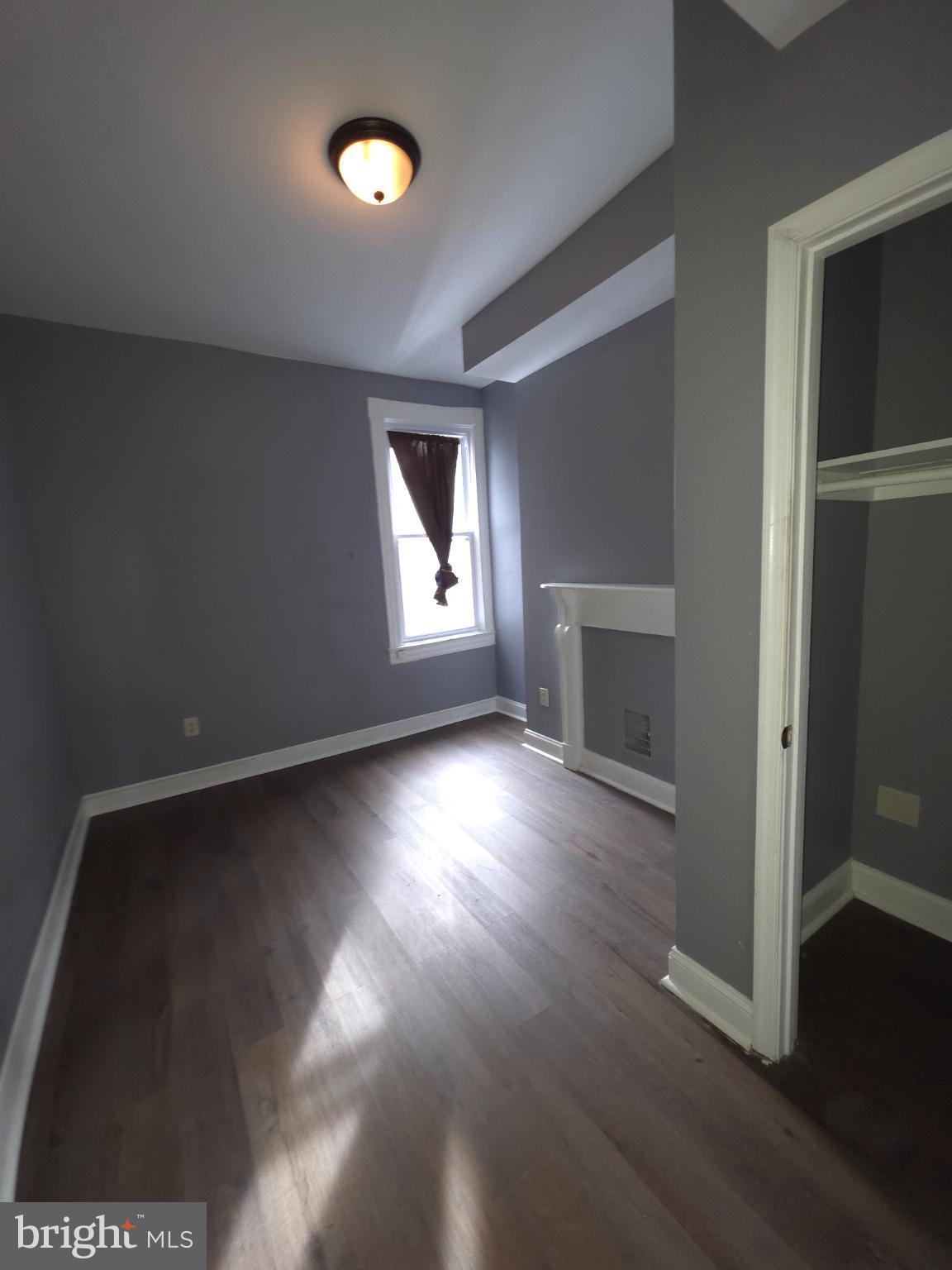 2617 East Preston Street Baltimore, MD 21213 - Photo 20 of 30 an empty room with wooden floor fireplace and windows