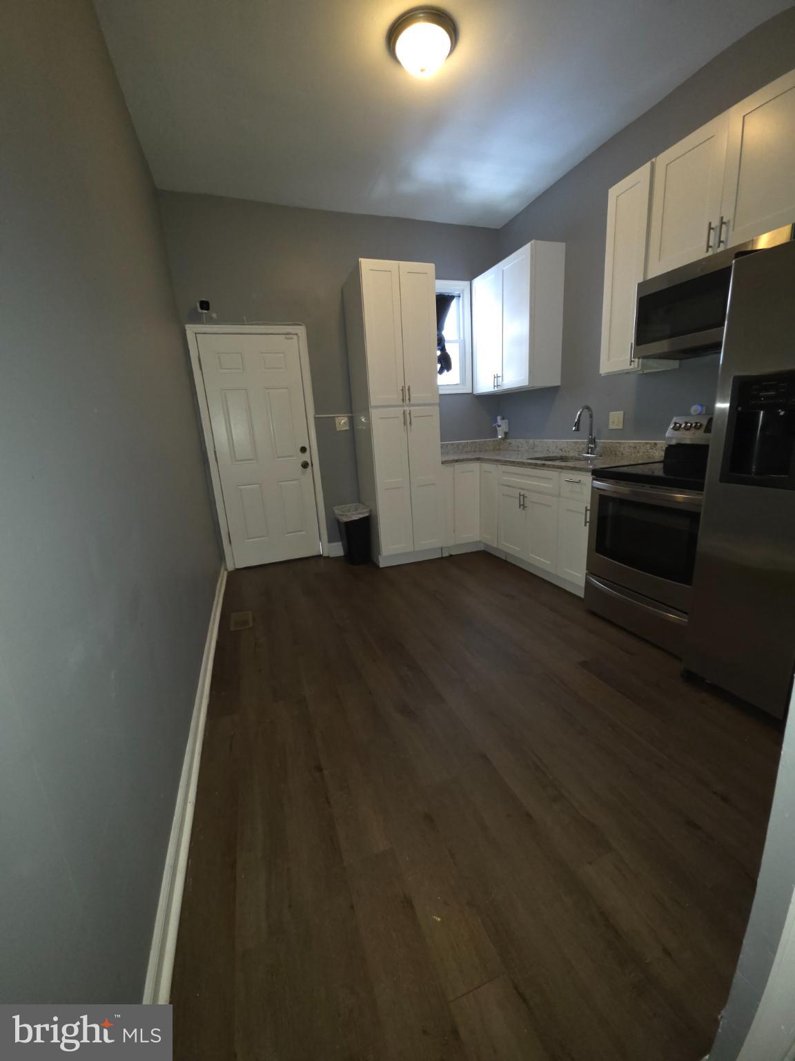 2617 East Preston Street Baltimore, MD 21213 - Photo 3 of 30 a view of a kitchen with wooden floor and electronic appliances