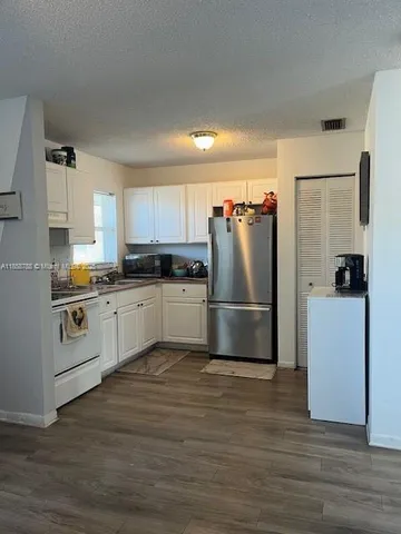 a kitchen with granite countertop a refrigerator and a stove top oven