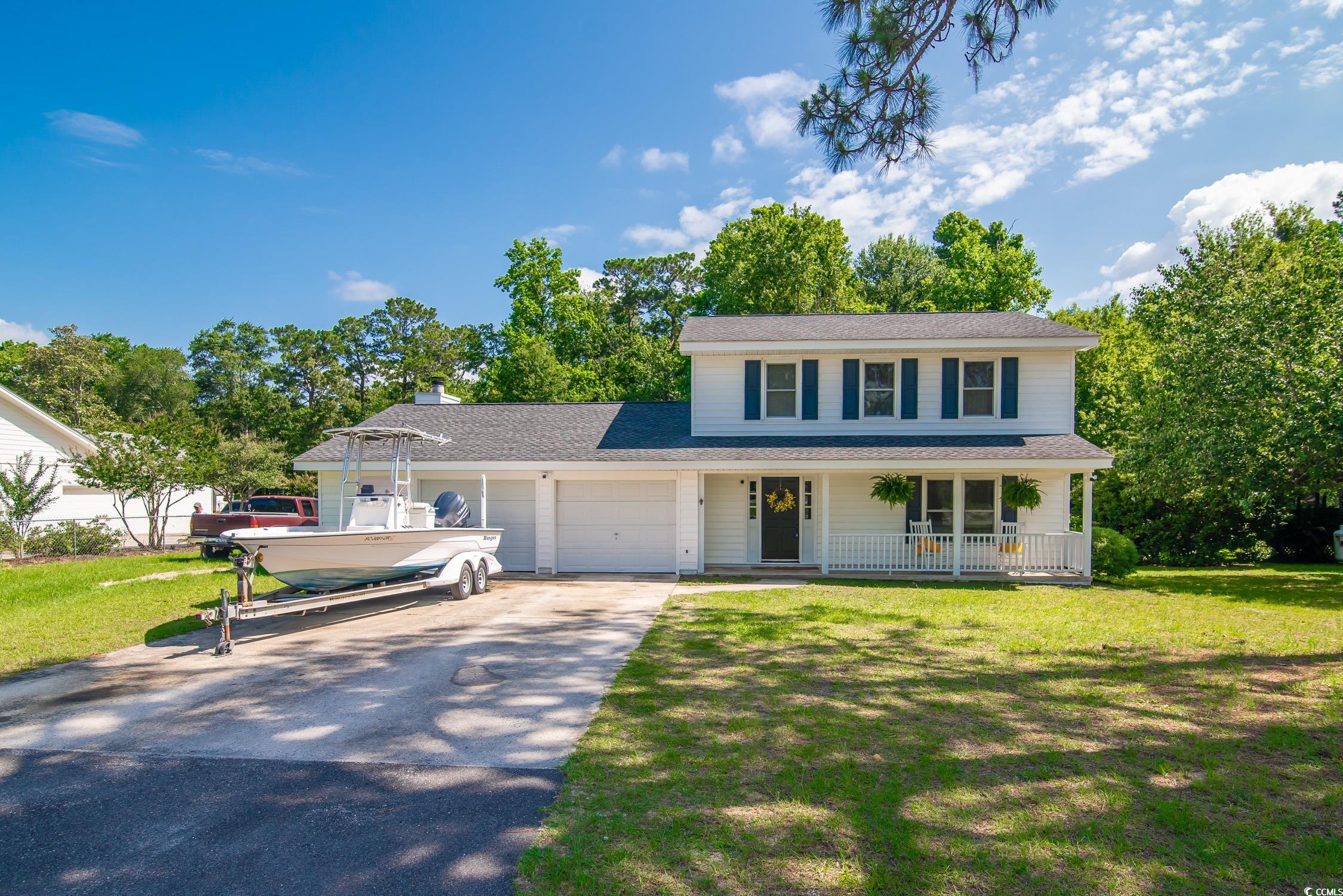 66 Johnstone Lane Georgetown, SC 29440 - Photo 3 of 40 Traditional-style home with covered porch, asphalt driveway, an attached garage, and a front yard