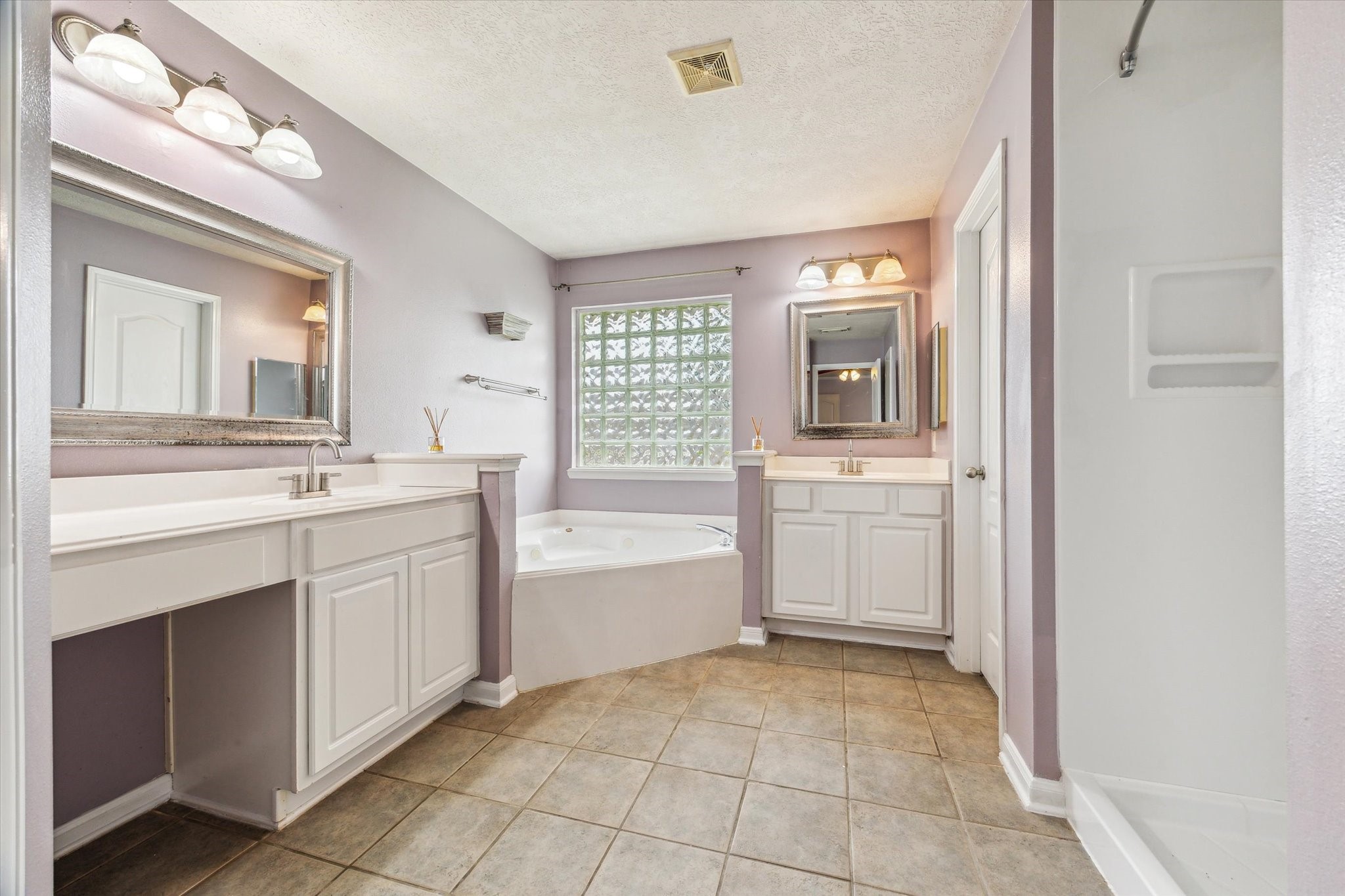 5716 Meadow Breeze Lane Rosharon, TX 77583 - Photo 15 of 24 Master bathroom-Enjoy everyday luxury in the ensuite bath, complete with a separate shower and oversize seated jetted tub—ideal for unwinding after a long day. A double-sink vanity with a large mirror and beautiful light fixtures enhances functionality, while the thoughtful layout ensures privacy and comfort within the suite.