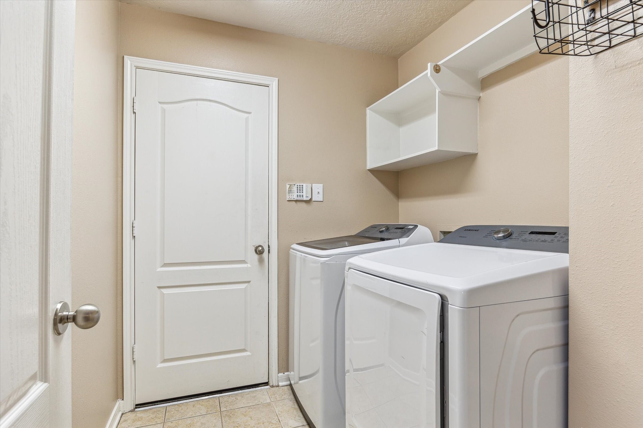 5716 Meadow Breeze Lane Rosharon, TX 77583 - Photo 21 of 24 Landryroom has direct access to the garage, offering both convenience and functionality for everyday living. Tile-look flooring and wall-mounted shelving make it easy to keep things organized. Washer and Dryer stays with sale.