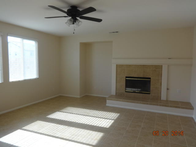 43660 Windrose Place Lancaster, CA 93536 - Photo 3 of 8 a room with a fireplace and a ceiling fan