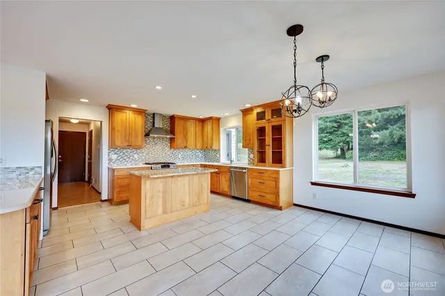 a large kitchen with granite countertop a large counter top a sink stainless steel appliances and cabinets