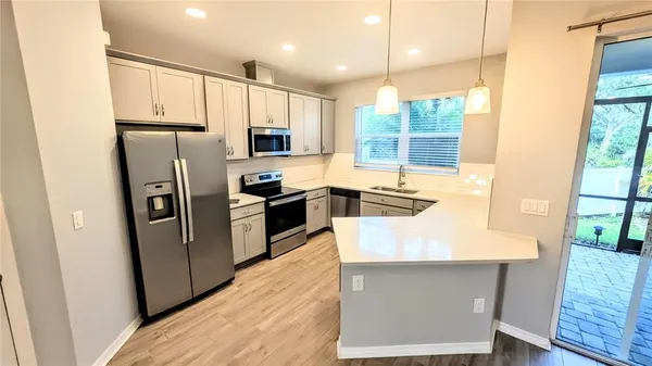 a kitchen with stainless steel appliances a refrigerator a sink a stove a table and chairs