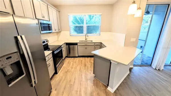 a kitchen with stainless steel appliances a stove a sink a refrigerator a window and a counter top space