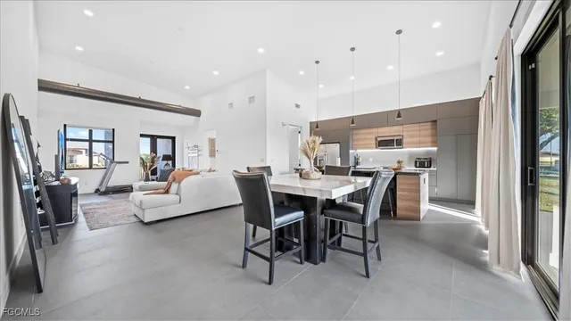 a living room with furniture and a dining table with projector the kitchen