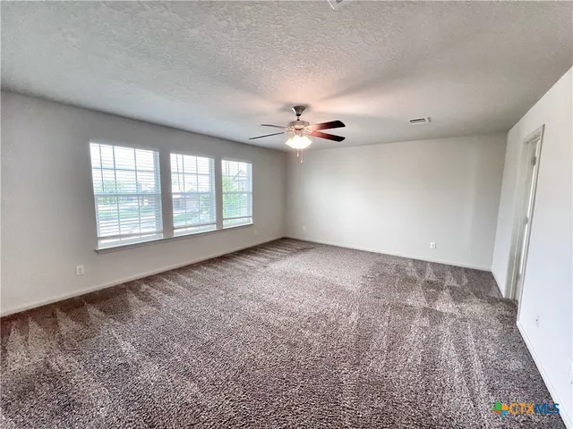 an empty room with windows and chandelier fan