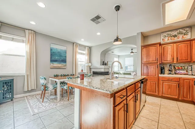 a kitchen with stainless steel appliances granite countertop a sink a stove a dining table and chairs