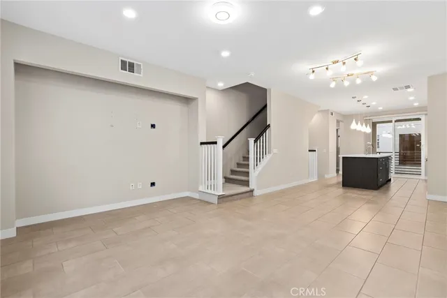 an empty room with staircase and kitchen view