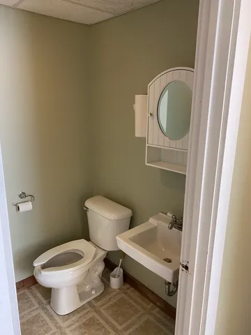 a white toilet sitting next to a bathroom sink and a mirror