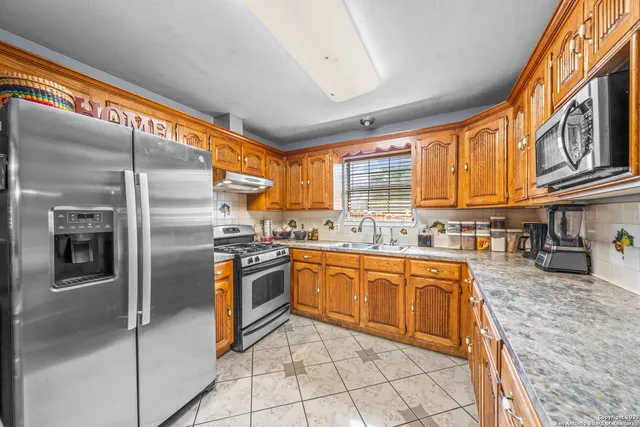 a kitchen with stainless steel appliances granite countertop a refrigerator and a sink