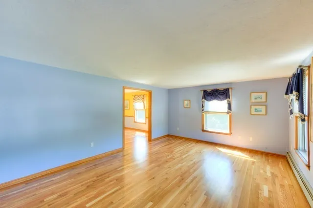 a view of an empty room with window and wooden floor