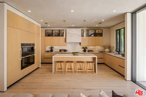 a large white dining hall with stainless steel appliances granite countertop a stove and a refrigerator