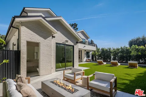 a view of a white house with a big yard and potted plants