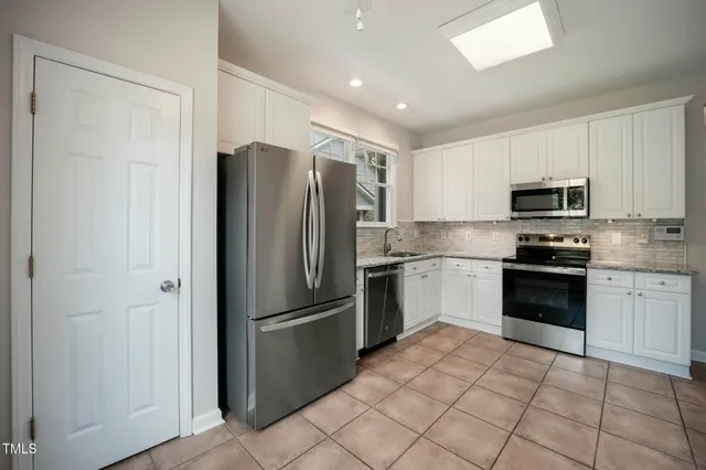 an empty room with a chandelier fan and windows