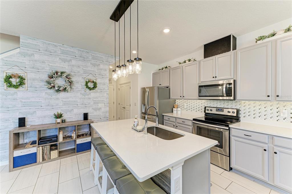 11637 Woodleaf Drive Lakewood Ranch, FL 34211 - Photo 11 of 54 a kitchen with stainless steel appliances a stove sink microwave and cabinets
