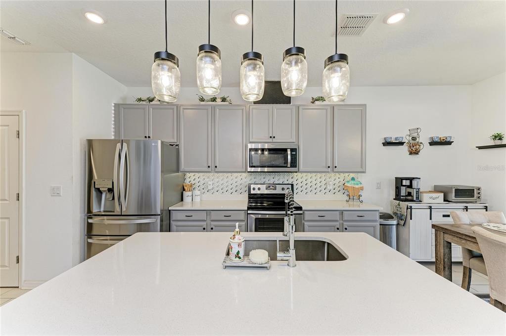 11637 Woodleaf Drive Lakewood Ranch, FL 34211 - Photo 12 of 54 a kitchen with stainless steel appliances a sink a stove a refrigerator and cabinets