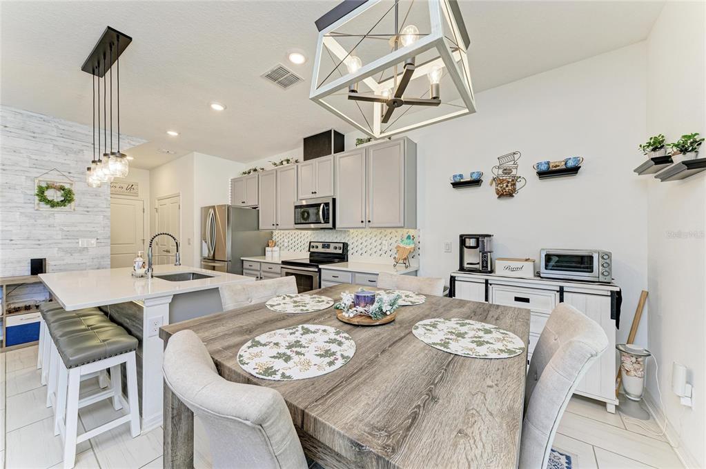 11637 Woodleaf Drive Lakewood Ranch, FL 34211 - Photo 9 of 54 a kitchen with stainless steel appliances kitchen island granite countertop a stove a sink a dining table and chairs with wooden floor