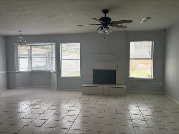 an empty room with windows and fireplace