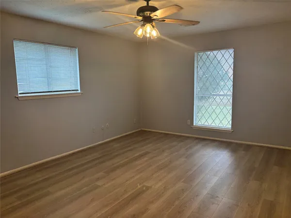 a view of an empty room with window and wooden floor