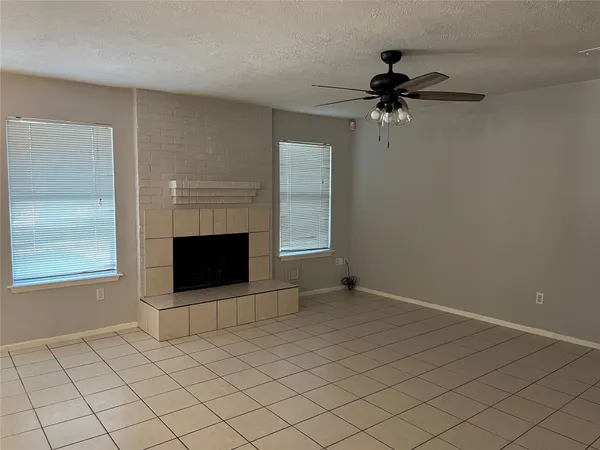 an empty room with windows and fireplace