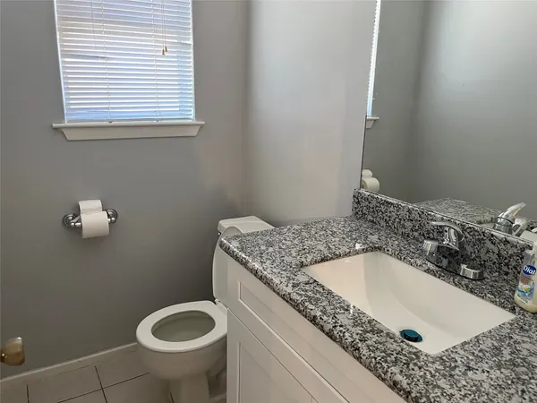 a bathroom with a granite countertop sink and a toilet