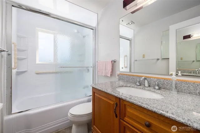 a bathroom with a granite countertop sink a toilet and shower