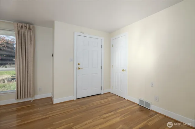 a view of an empty room with wooden floor and a window