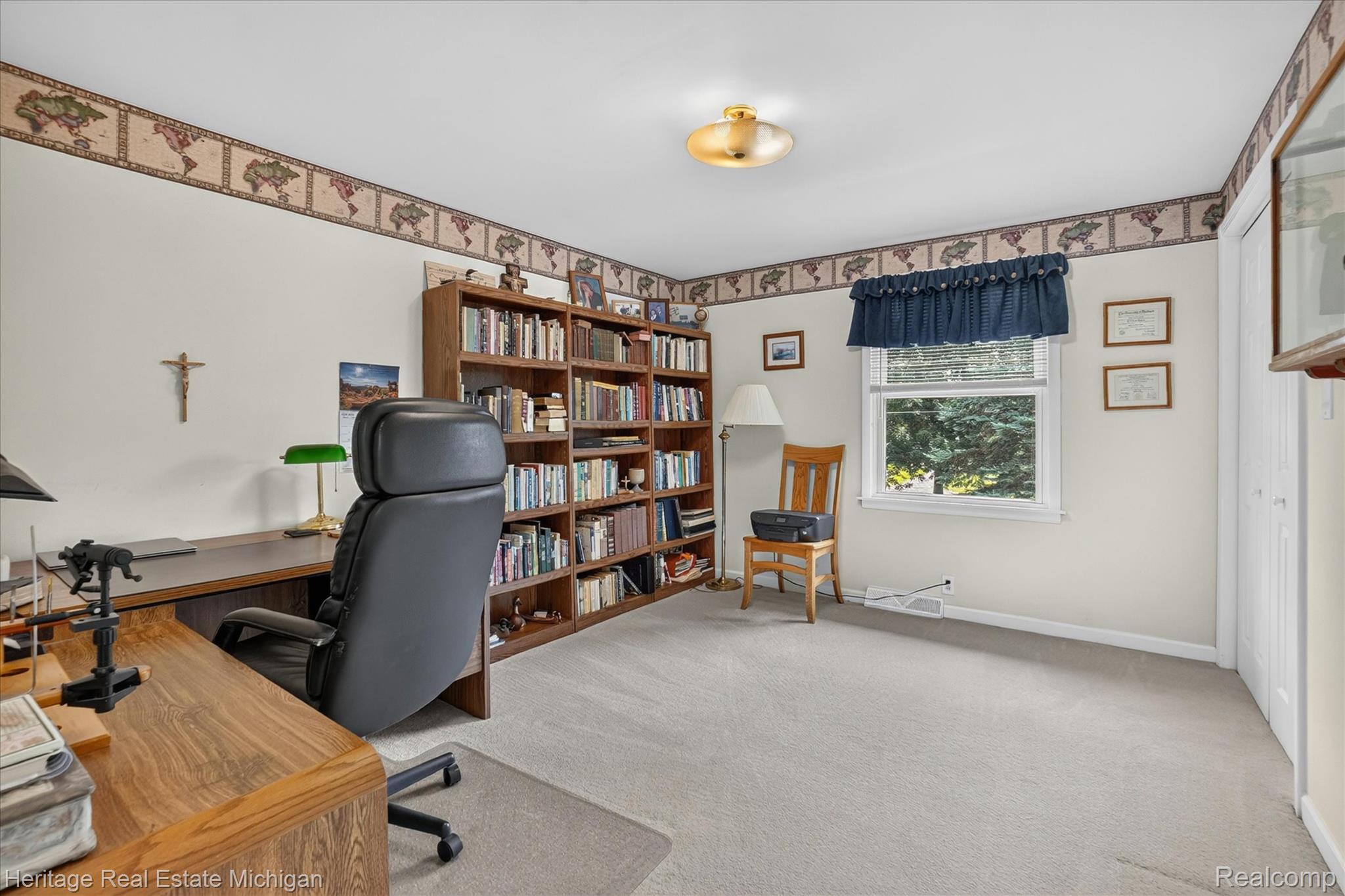 14038 North Hogan Road Linden, MI 48451 - Photo 9 of 53 Spacious interior room featuring light-toned walls, a built-in bookshelf, wall-to-wall carpeting, a window with exterior tree views, and a flush-mount ceiling light fixture