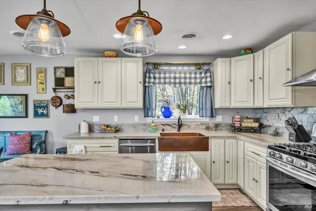 a kitchen with stainless steel appliances granite countertop a stove a sink and a white cabinets
