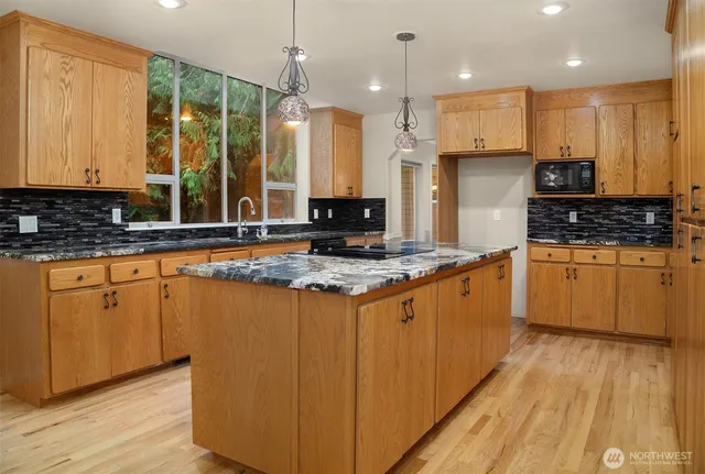a large kitchen with stainless steel appliances kitchen island a large counter top and a wooden floors