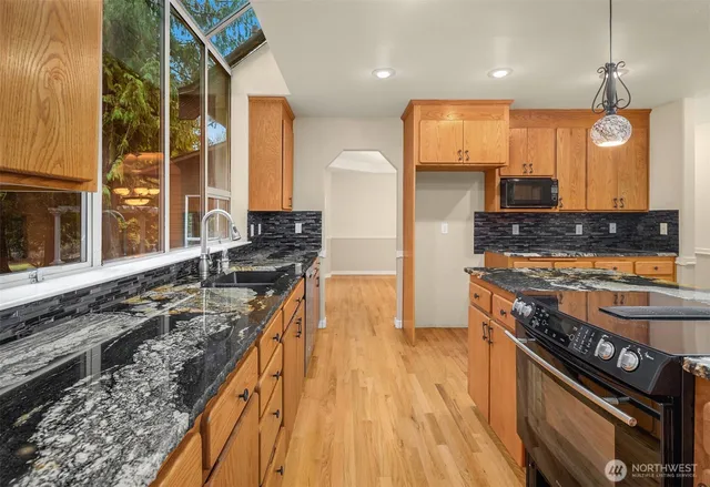 a kitchen with stainless steel appliances granite countertop a stove top oven a refrigerator with wooden floors and cabinets