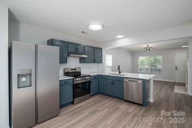 a large kitchen with stainless steel appliances granite countertop a stove a sink dishwasher and a refrigerator