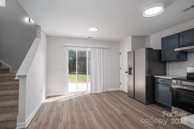 a view of a kitchen with refrigerator and wooden floor