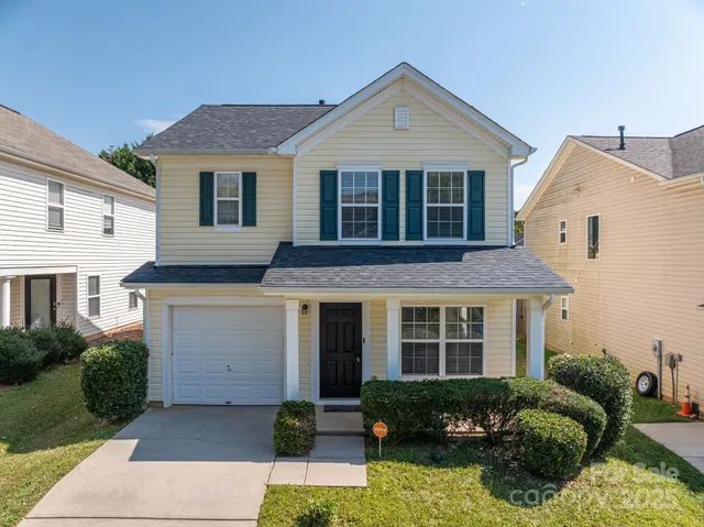 a front view of a house with a yard and potted plants