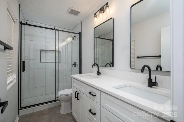 a bathroom with a double vanity sink mirror and shower