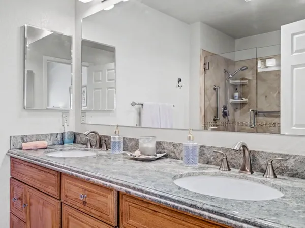 a bathroom with double vanity sinks granite vanity and a mirror
