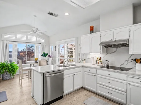 a kitchen with white cabinets and sink