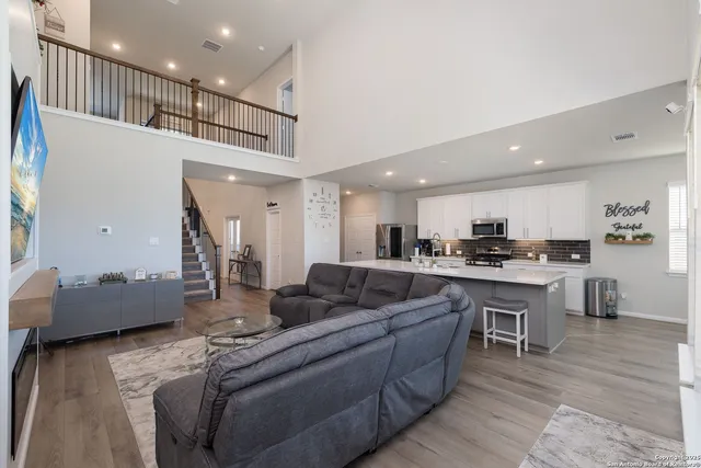 a living room with furniture kitchen view and a wooden floor