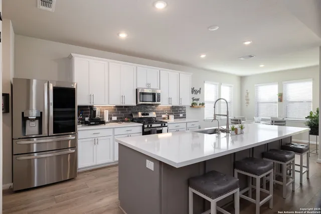a kitchen with a sink stainless steel appliances and white cabinets