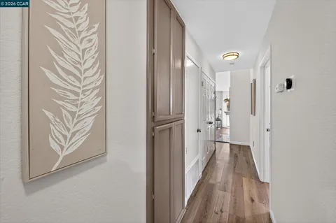 a view of a hallway with wooden floor and closet