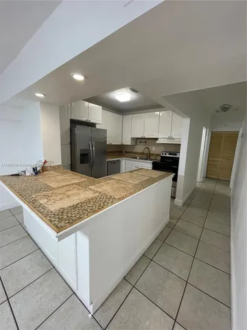 a kitchen with kitchen island granite countertop a stove sink and cabinets