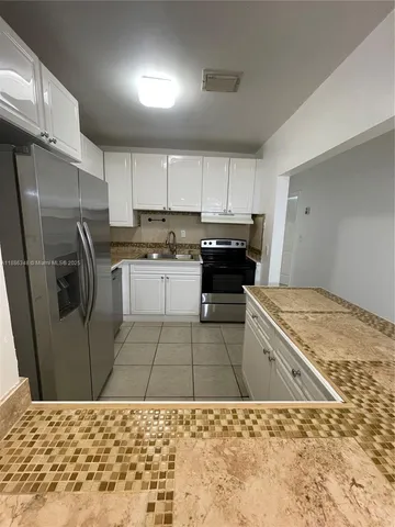 a kitchen with a sink a refrigerator and cabinets