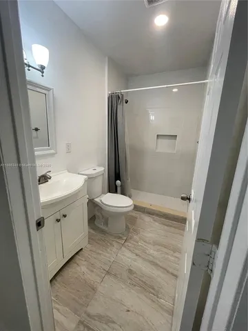 a bathroom with a sink a toilet a mirror and shower