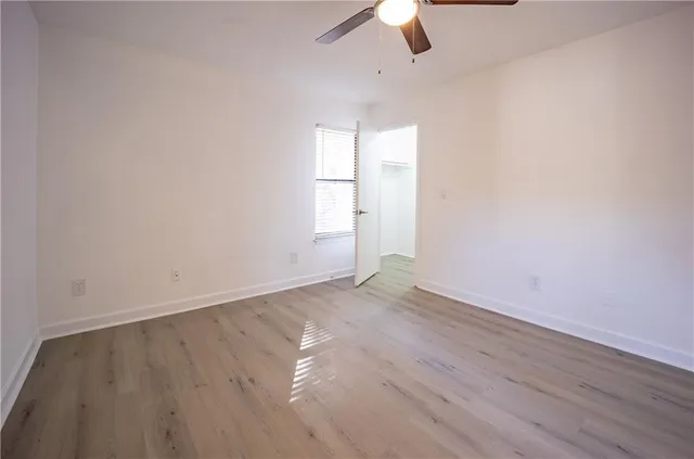 an empty room with wooden floor ceiling fan and window